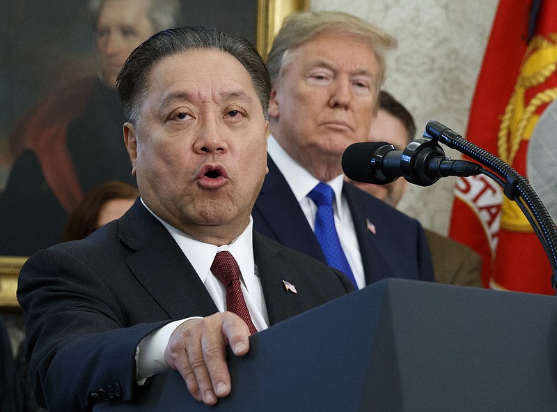 In this Thursday, Nov. 2, 2017, file photo, Broadcom CEO Hock Tan speaks while U.S. President Donald Trump listens, in background, during an event at the White House in Washington, to announce the company is moving its global headquarters to the United States. In a decision announced Monday, March 12, 2018, Trump is blocking Singapore chipmaker Broadcom from pursuing a hostile takeover of U.S. rival Qualcomm on the grounds that the combination would threaten national security. (AP Photo/Evan Vucci, File)