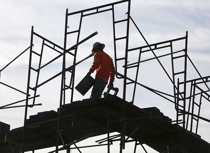 Workers move concrete bricks into place on a stairwell and elevator shaft at the construction site of a 189-unit apartment complex being built last October on Somerville Avenue.