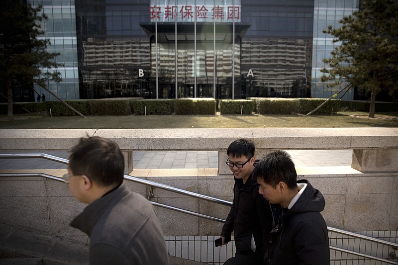 
              FILE - In this Feb. 23, 2018, file photo, people walk past offices of the Anbang Insurance Group in Beijing. China's government announced plans Tuesday, March 13, 2018, to create a newly powerful regulator to oversee scandal-plagued banking and insurance industries as they try to reduce debt and financial risks. (AP Photo/Mark Schiefelbein)
            