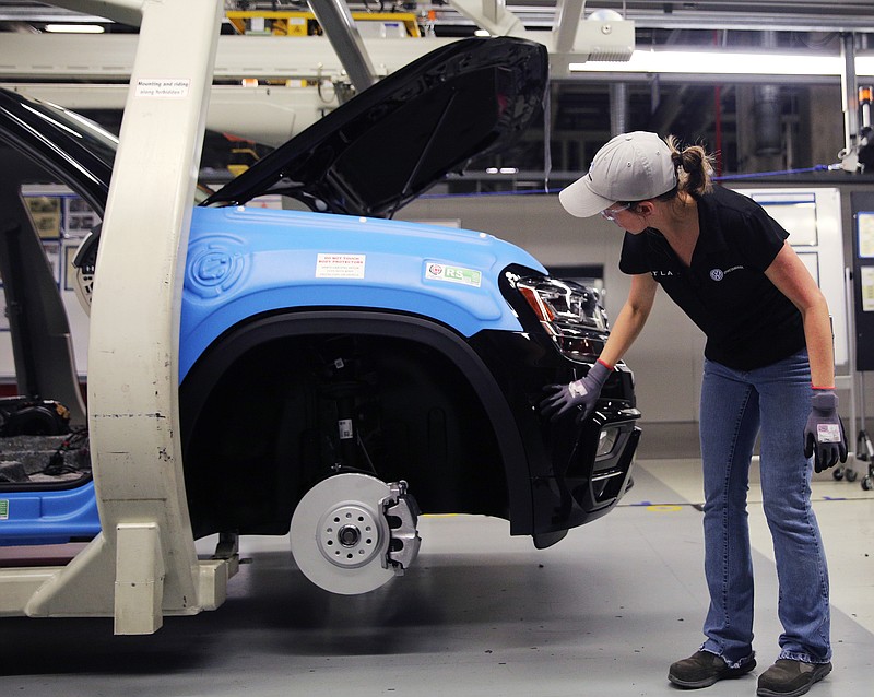 Staff file photo by Erin O. Smith / A Volkswagen employee walks around the outside of a vehicle inspecting different parts at the automaker's Chattanooga assembly plant.