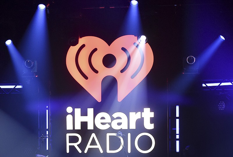 FILE- In this Nov. 7, 2017, file photo, the logo for iHeartRadio, owned by iHeartMedia, Inc., is shown during an album release party with Maroon 5 in Burbank, Calif. IHeartMedia, one of the world’s largest radio and billboard companies, has filed for Chapter 11 bankruptcy protection. The San Antonio-based iHeartMedia Inc., which was formerly Clear Channel Communications, said Thursday, March 15, 2018, that it has reached an agreement with the holders of more than $10 billion of its debt and will restructure its finances as a result. (Photo by Richard Shotwell/Invision/AP, File)