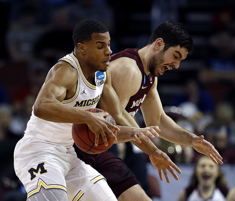 Montana forward Fabijan Krslovic, right, tries to steal the ball from Michigan guard Jaaron Simmons, left, during the first half of an NCAA men's college basketball tournament first-round game Thursday, March 15, 2018, in Wichita, Kan. (AP Photo/Charlie Riedel)