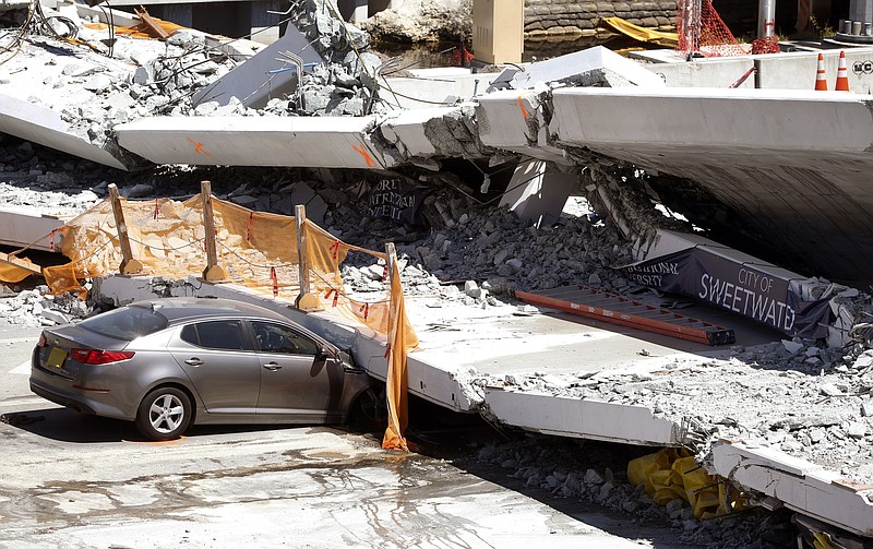 Crushed cars are shown under a section of a collapsed pedestrian bridge, Friday, March 16, 2018 near Florida International University in the Miami area. 