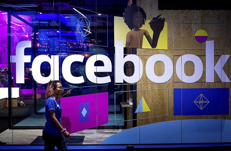 FILE - In this April 2017 file photo, a conference worker passes a demo booth at Facebook's annual developer conference, in San Jose, Calif. (AP Photo/Noah Berger, File)
