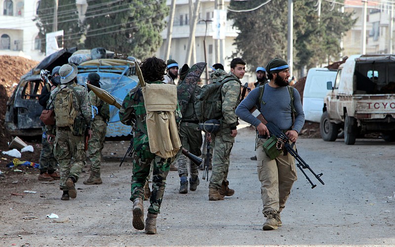 
              Turkey-backed Free Syrian Army soldiers walk in the city center of Afrin, northwestern Syria, early Sunday, March 18, 2018. Turkey's President Recep Tayyip Erdogan said Sunday that allied Syrian forces have taken "total" control of the town center of Afrin, the target of a nearly two-month-old Turkish offensive against a Syrian Kurdish militia, which said fighting was still underway. Erdogan said the Turkish flag and the flag of the Syrian opposition fighters have been raised in the town, previously controlled by the Kurdish militia known as the People's Defense Units, or YPG. (Hasan Kirmizitas/DHA-Depo Photos via AP)
            