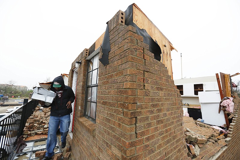 Brian Smith, a student at Jacksonville State University, carries his belongings out of his apartment, Tuesday, March 20, 2018, after a violent storm went swept through Jacksonville, Ala., the night before. Smith said he was forced to climb out of his apartment with a sheet connected to a metal rail fence to get out safely from the second floor. (AP Photo/Brynn Anderson)