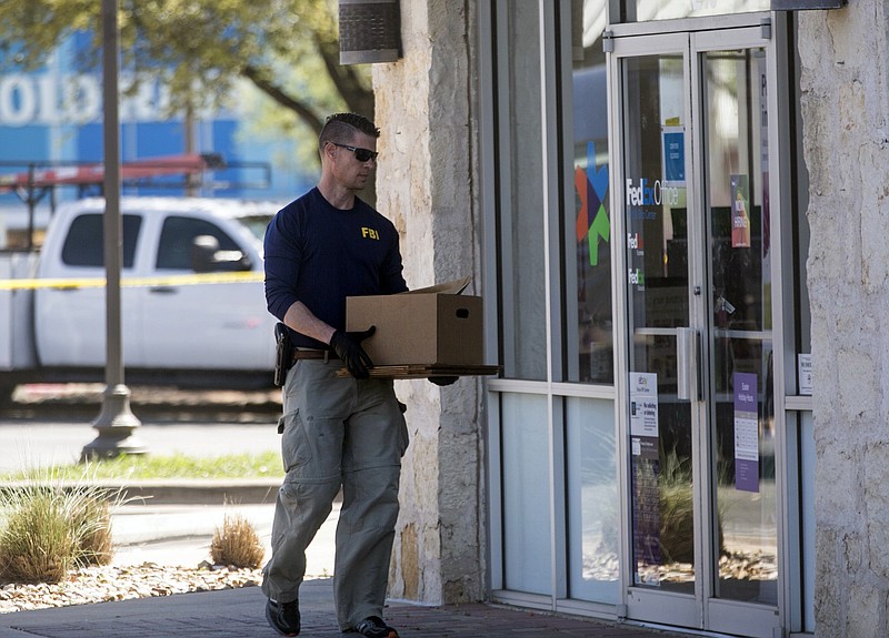An FBI official carries items into a FedEX Office store Tuesday, March 20, 2018, in the southwest Austin suburb of Sunset Valley, Texas, as authorities investigate a recent string of package bombs. (Reshma Kirpalani/Austin American-Statesman via AP)