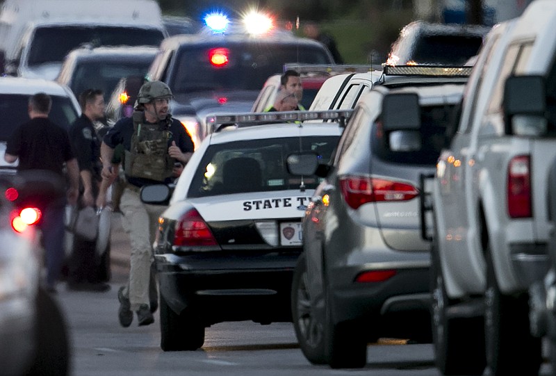 A law enforcement officer runs on Brodie Lane in Austin, Texas, moments after an explosion on Tuesday, March 20, 2018. Emergency teams were responding Tuesday night to another reported explosion in Texas' capital, this one at a Goodwill store in the southern part of the city. (Jay Janner/Austin American-Statesman via AP)