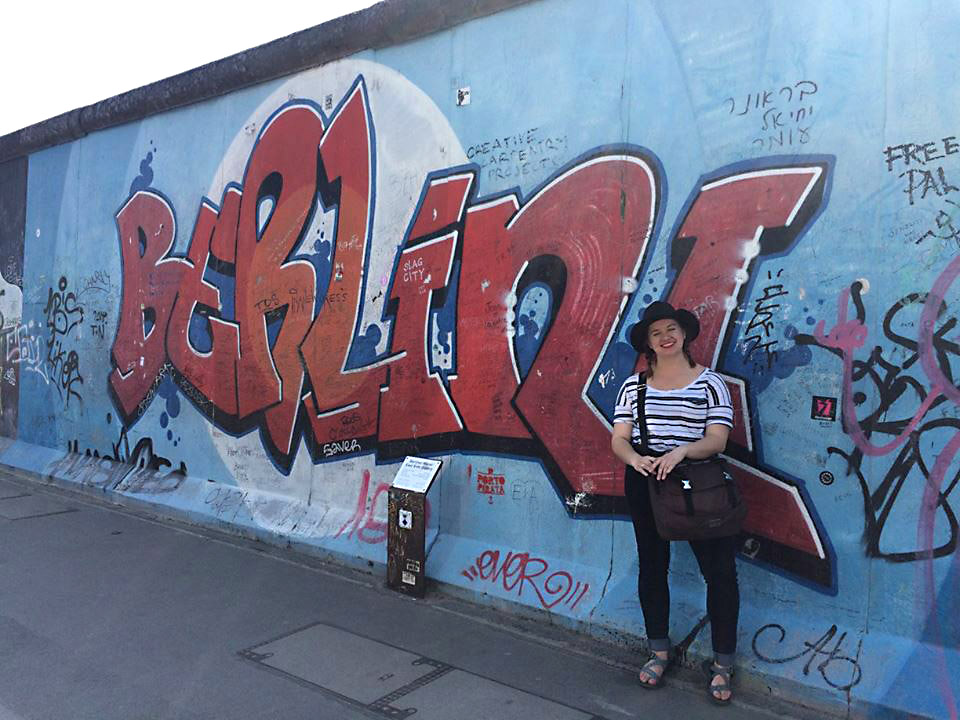 Carson Cook poses in front of a mural on the East Side Gallery, one of the remaining sections of the Berlin Wall.