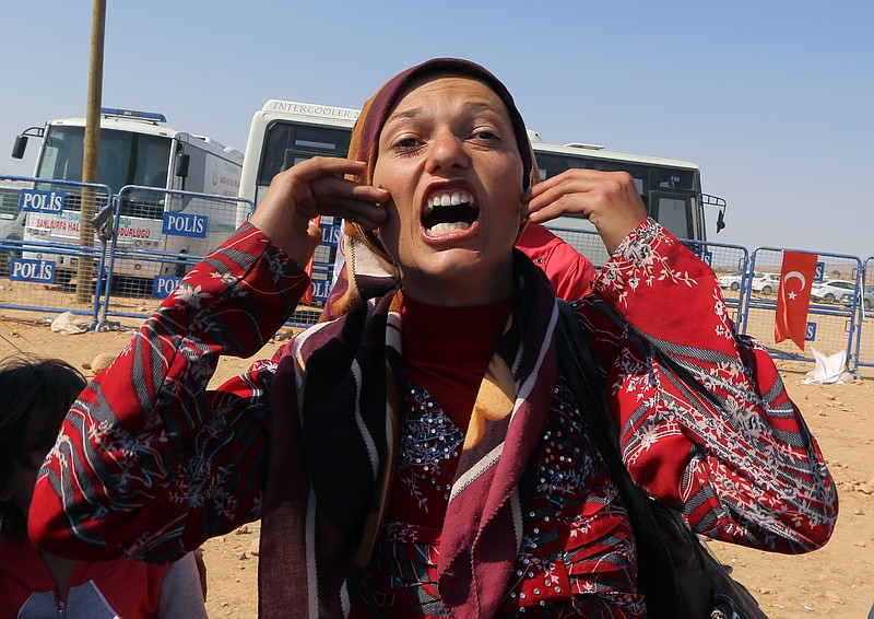 A Syrian Kurdish refugee shouts, "Where are the big powers, where is humanity?" after she arrived at the Turkey-Syria border crossing in 2014.