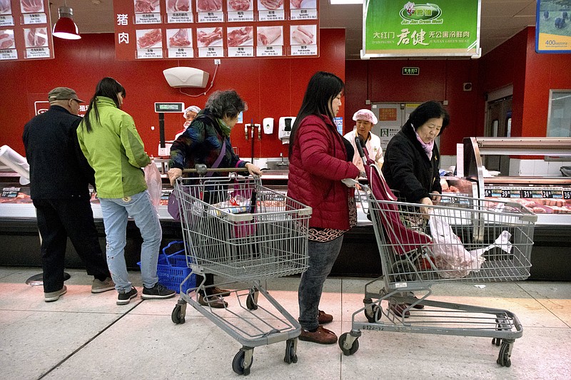 Customers shop for pork at a supermarket in Beijing, Friday, March 23, 2018. China announced a $3 billion list of U.S. goods including pork, apples and steel pipe on Friday that it said may be hit with higher tariffs in a spiraling trade dispute with President Donald Trump that companies and investors worry could depress global commerce. (AP Photo/Mark Schiefelbein)
