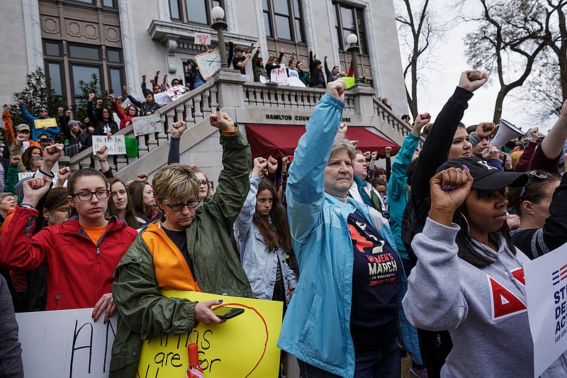 Demonstrators raise their fists during a moment of silence on the steps of the Hamilton County Courthouse during the March for Our Lives on Saturday, March 24, 2018, in Chattanooga, Tenn. Thousands of demonstrators marched locally in solidarity with national protests against gun violence spurred by last month's school shooting in Parkland, Fla.