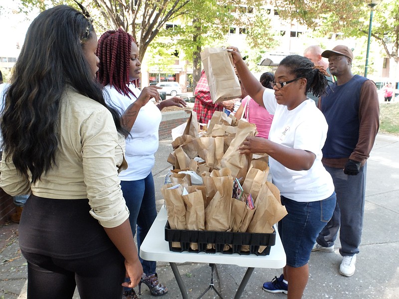 Eastern Star member Demetrus Coonrod, right, prepares sack lunches and gift bags for the homeless at Miller Park on Friday. From left are, Brianna Green, Rozetta Bonds, Coonrod and Richard Williams.