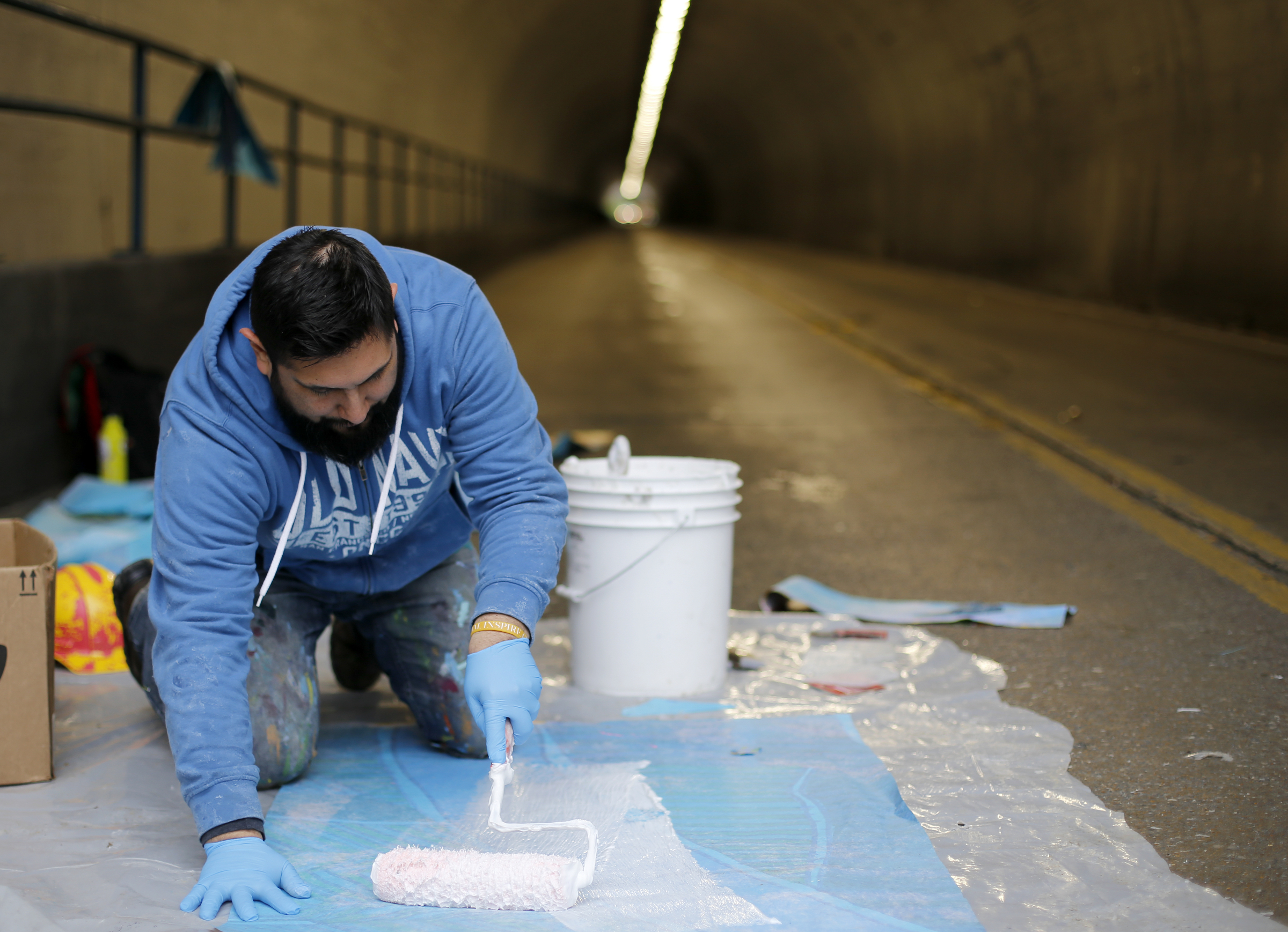Local artist Alex Paul Loza applies glue to the back side of a section of the mural to go up on the east end of the Wilcox Tunnel on Monday, March 26, 2018 in Chattanooga, Tenn. Loza was working with the GoodSpace Murals crew to put up the mural on each end of the Wilcox Boulevard Tunnel.