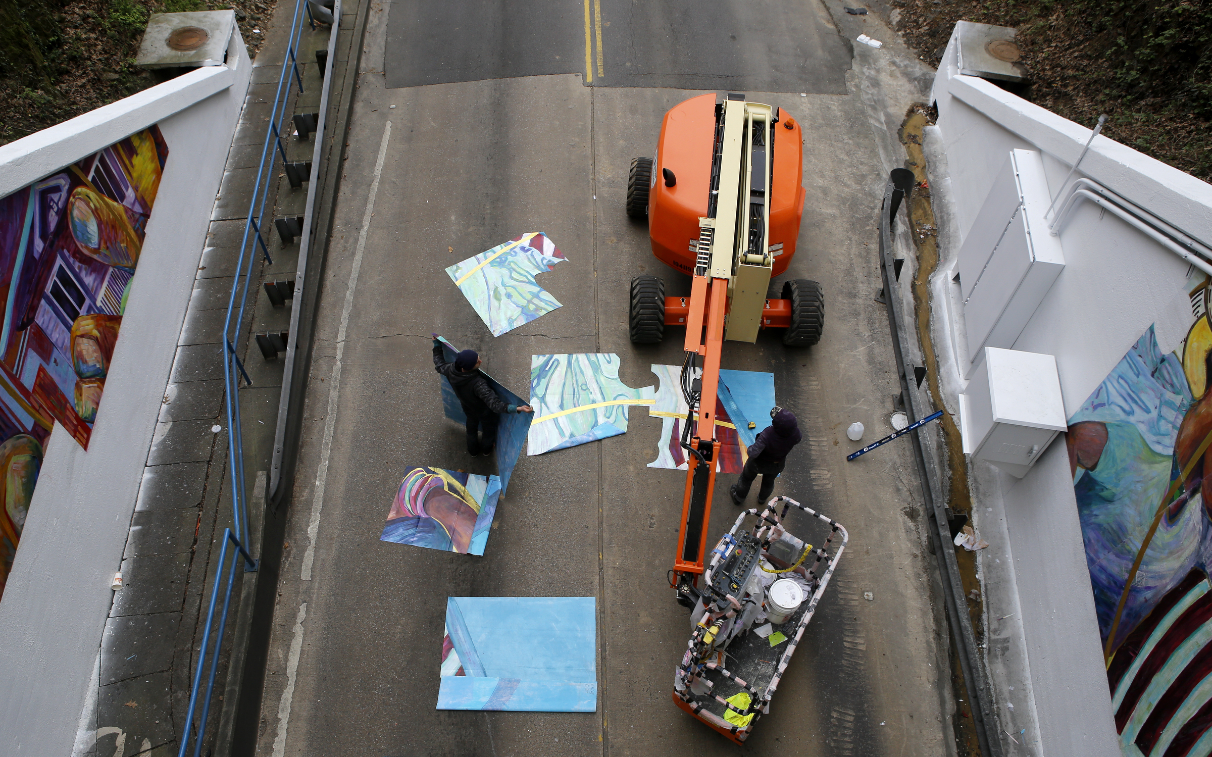 Eamonn McLain, left, and Tina Monje work on cutting out sections of the mural for the west end of the Wilcox Tunnel on Monday, March 26, 2018 in Chattanooga, Tenn. McLain and Monje are apart of the GoodSpace Murals crew out of Minneapolis.