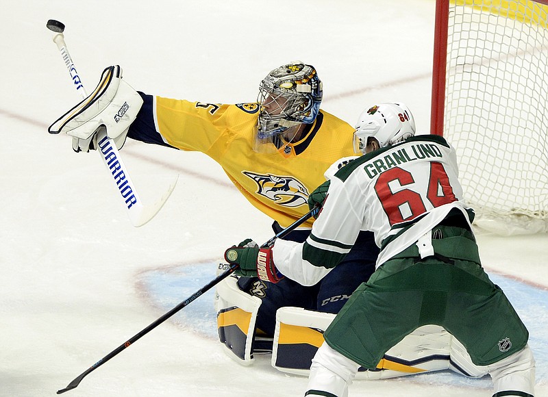 Nashville Predators goaltender Pekka Rinne (35), of Finland, blocks a shot with his stick as Minnesota Wild right wing Mikael Granlund (64), of Finland, looks for the rebound during the second period of an NHL hockey game Tuesday, March 27, 2018, in Nashville, Tenn. (AP Photo/Mark Zaleski)