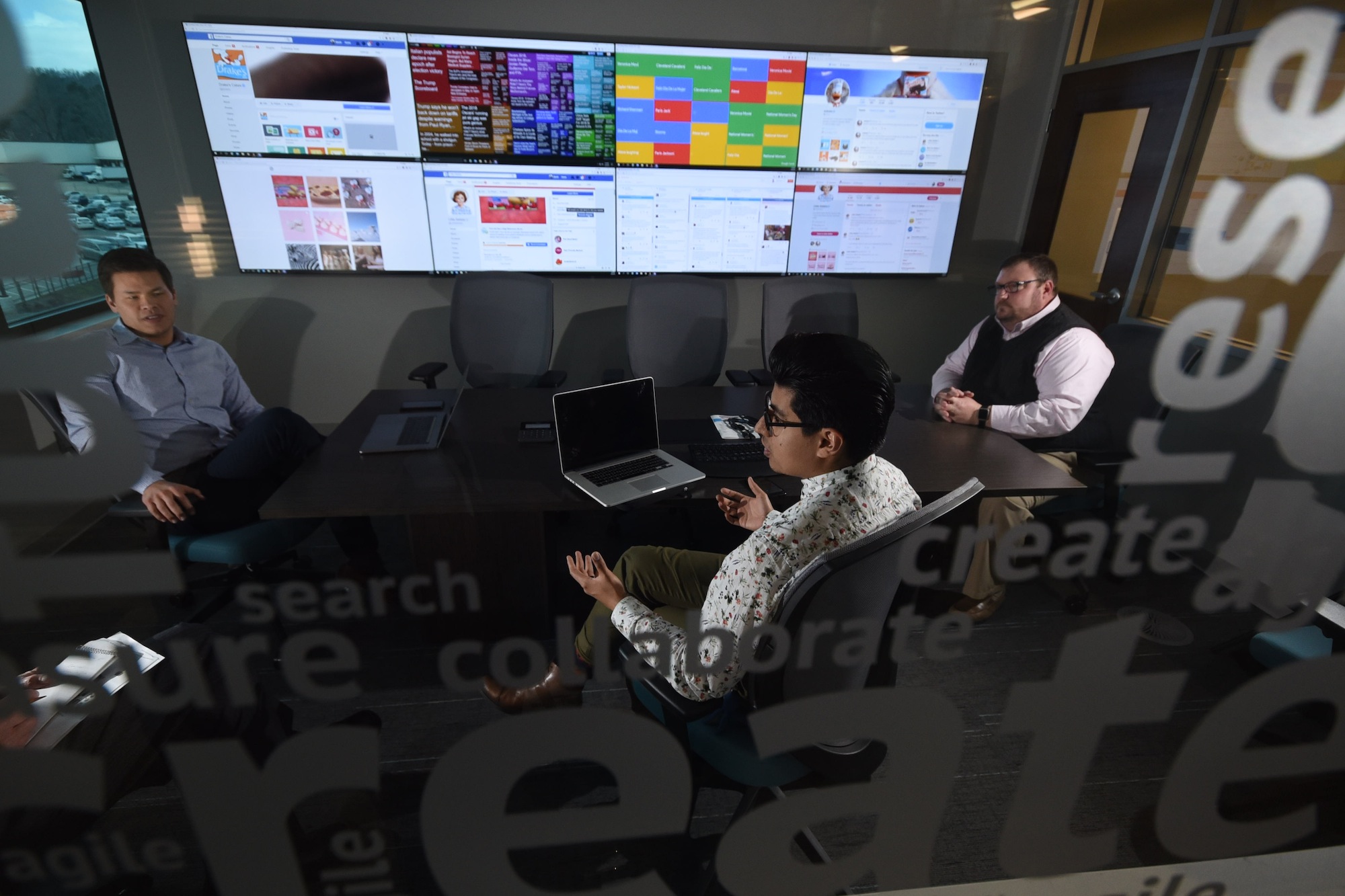 McKee Foods David Blair, left, marketing and advertising specialist, and Bryant Rodriguez, digital and social media strategist, sit with Mike Gloekler, far right, corporate communications and public relations manager in the social media center inside the Collegedale Corporate offices.