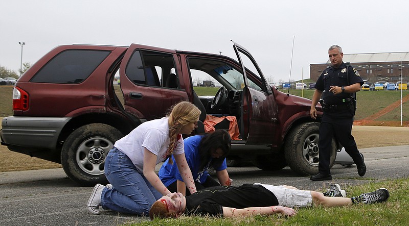 A police officer arrives on the scene to find students Micayla Rowan {CQ}, left, and Brooklin Hodges {CQ} reacting to finding Gage Dennis on the ground during a simulated crash at Robert Talaska Field on the campus of Soddy-Daisy High School on Wednesday, March 28, 2018 in Soddy-Daisy, Tenn.