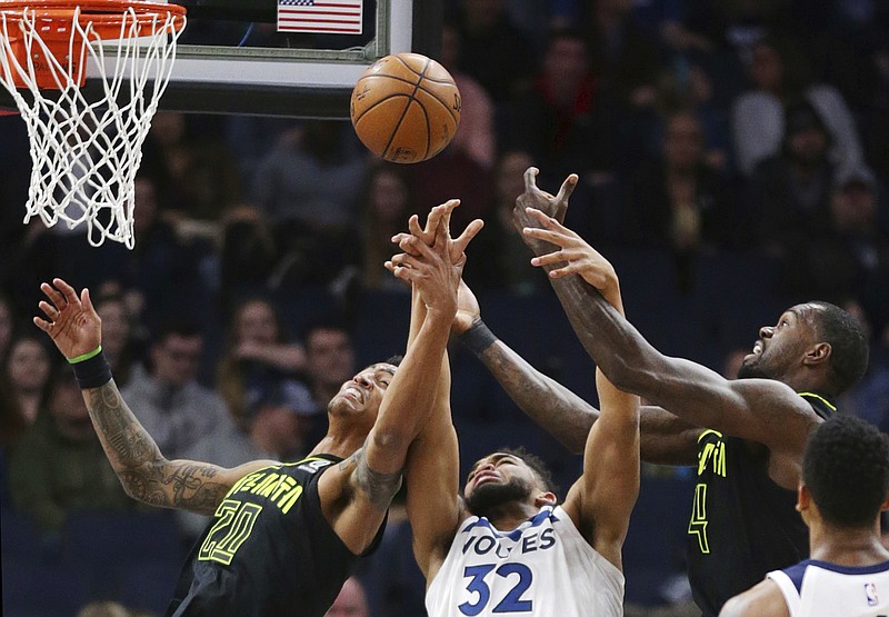 Minnesota Timberwolves forward Karl-Anthony Towns (32) vies for a rebound with Atlanta Hawks forwards Dewayne Dedmon (14) and John Collins (20) during the first quarter of an NBA basketball game Wednesday, March 28, 2018, in Minneapolis. (AP Photo/Andy Clayton-King)
