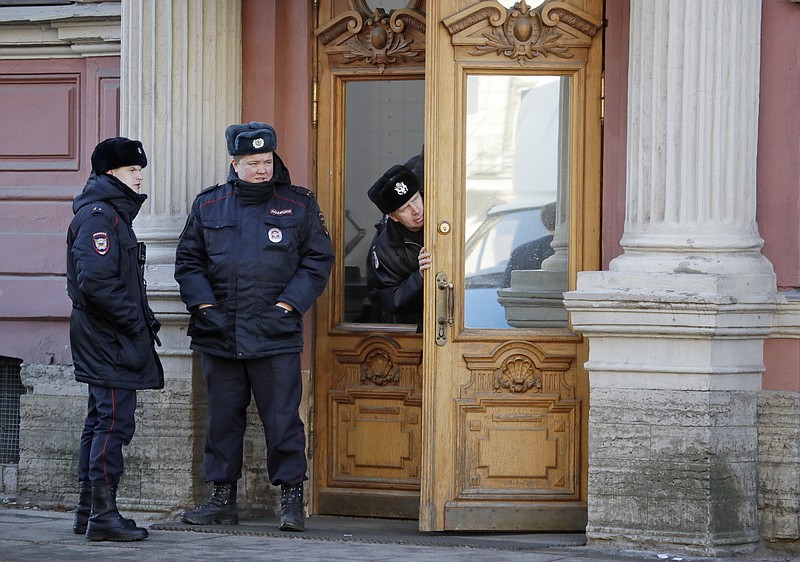 A security guard peeks out the door as Russian police officers guard the entrance, at the U.S. consulate in St.Petersburg, Russia, Saturday, March 31, 2018. 