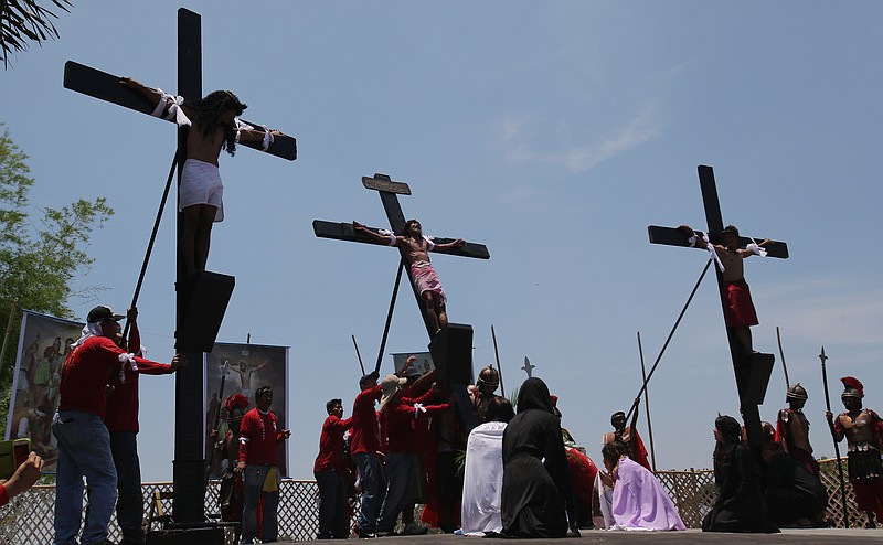 A Filipino man, center, portrays Jesus Christ in a re-enactment of the crucifixion of Christ in a village of the Pampanga province in northern Philippines in 2014.