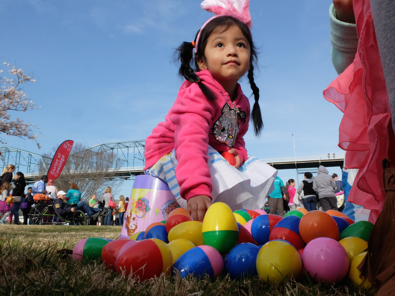Content With Her Batch -- Little Juliette Fuentes, 3, smiles as she sits on her bucket following the Easter at Coolidge egg hunt.
