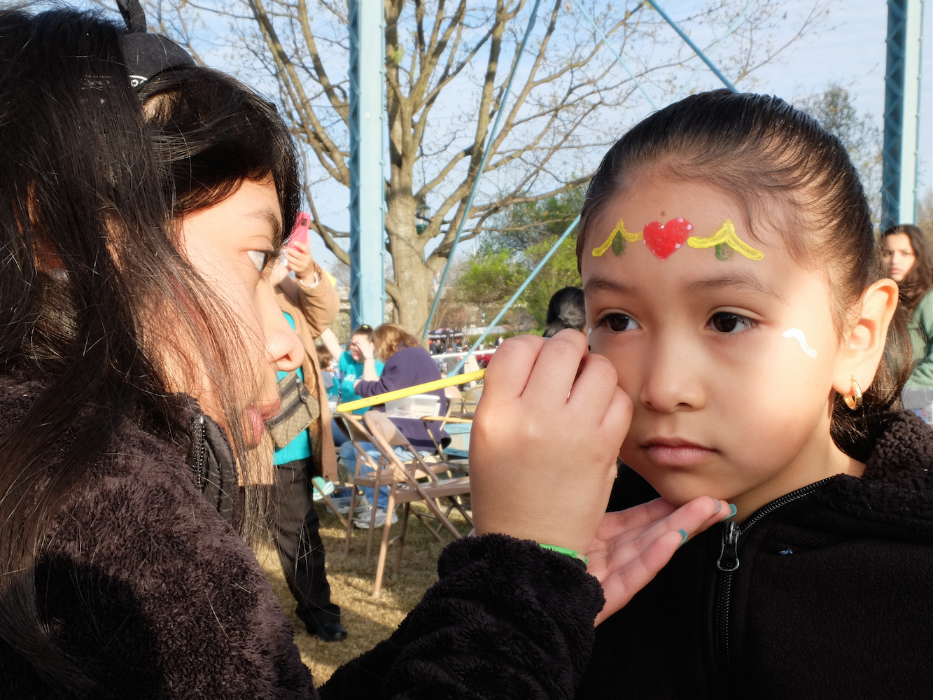 Rosa Vacquez, right, 7, has decorative face painting done by Brenda Deleon, a representative from Iglesia Bautista de Chattanooga Sunday morning during the 10th annual Easter at Coolidge celebration.