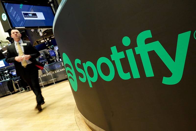 A trading post sports the Spotify logo on the floor of the New York Stock Exchange, Tuesday, April 3, 2018. Spotify, the No. 1 music streaming service which has drawn comparisons to Netflix, is about to find out how it plays on the stock market in an unusual IPO. (AP Photo/Richard Drew)