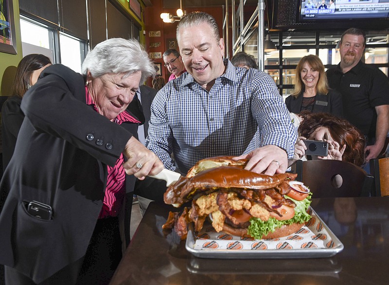 Big Daddy's Southeast Regional Manager Nick Leach, right, assists Pam Ladd in cutting a 10-pound burger at the opening of the Gunbarrel Road establishment on Tuesday.
Big Daddy's contributed $1,000 to the Partnership for Families, Children and Adults during opening ceremonies.