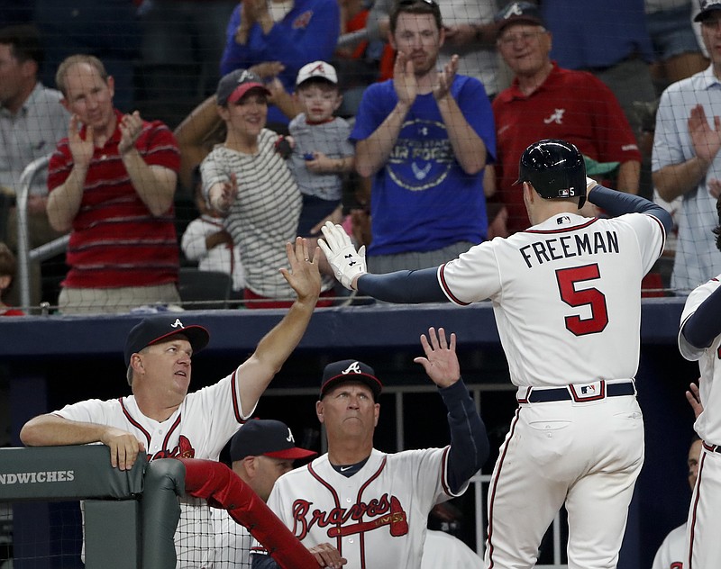 Atlanta Braves' Freddie Freeman (5) is greeted at the dugout by hitting coach Kevin Seitzer, left, and manager Brian Snitker after hitting a three-run home run during the second inning of the team's baseball game against the Washington Nationals on Tuesday, April 3, 2018, in Atlanta. (AP Photo/John Bazemore)