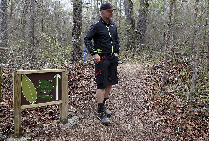 SORBA vice president Craig Lawson talks about the damage done along the Atlas Trial at Enterprise South Nature Park on Friday, April 6, 2018 in Chattanooga, Tenn. A vandalized sign can be seen on the left and a broken safety pole can be seen behind Lawson's right elbow.
