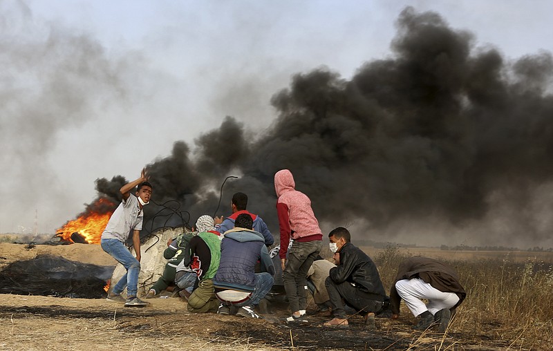Palestinian protesters cover during clashes with Israeli troops along Gaza's border with Israel, east of Khan Younis, Gaza Strip, Thursday, April 5, 2018. An Israeli airstrike in northern Gaza early on Thursday killed a Palestinian, while a second man died from wounds sustained in last week's mass protest. The fatalities bring to 21 the number of people killed in confrontations in the volatile area over the past week with a new round of protests along the border is expected on Friday. (AP Photo/Adel Hana)