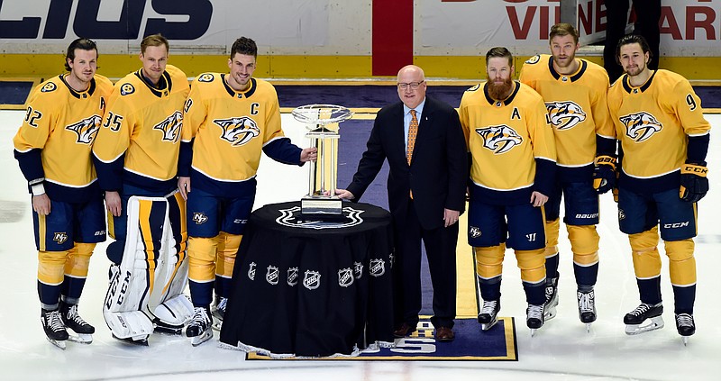 In this April 7, 2018, file photo, from left, Nashville Predators Ryan Johansen (92), Pekka Rinne (35), captain Roman Josi (59), National Hockey League Deputy Commissioner Bill Daly, Ryan Ellis (4), Mattias Ekholm (14), Filip Forsberg (9), stand next to the President's Trophy after accepting the trophy on behalf of the organization before an NHL hockey game against the Columbus Blue Jackets in Nashville, Tenn. The changing of the guard begins at the top, where Nashville clinched its first Central Division title by running away with the league's best record. (AP Photo/Mark Zaleski, File)
