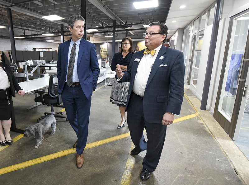 Chattanooga Mayor Andy Berke, left, walks with Office Furniture Warehouse owner John Jerman while touring the East Chattanooga business Tuesday before announcing business grants and initiatives.