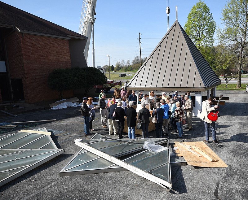 Pastor Chris Smith, right, removes his guitar after a group of church members sing, "Lift High the Cross," at Trinity Lutheran Church in Hixson Wednesday morning. The church is replacing the steeple after more than 40 years.