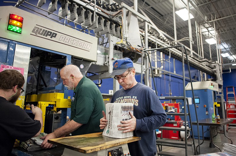 In this April 11, 2018, photo, production handler Pat Breidenbach straightens out a stack of newspapers while working at the Janesville Gazette Printing & Distribution plant in Janesville, Wis. Newspaper publishers across the U.S. already strapped by years of declining revenue say they're dealing with an existential threat: Recently imposed tariffs on Canadian newsprint driving up their business costs. (Angela Major/The Janesville Gazette via AP)