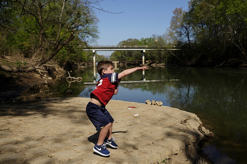 Peyton Ferrell tosses rocks into South Chickamauga Creek near the Sterchi Farm Greenway on Thursday, April 12, 2018, in Chattanooga, Tenn. His mother Rachel Ferrell says her family moved into the neighborhood specifically for the greenway.