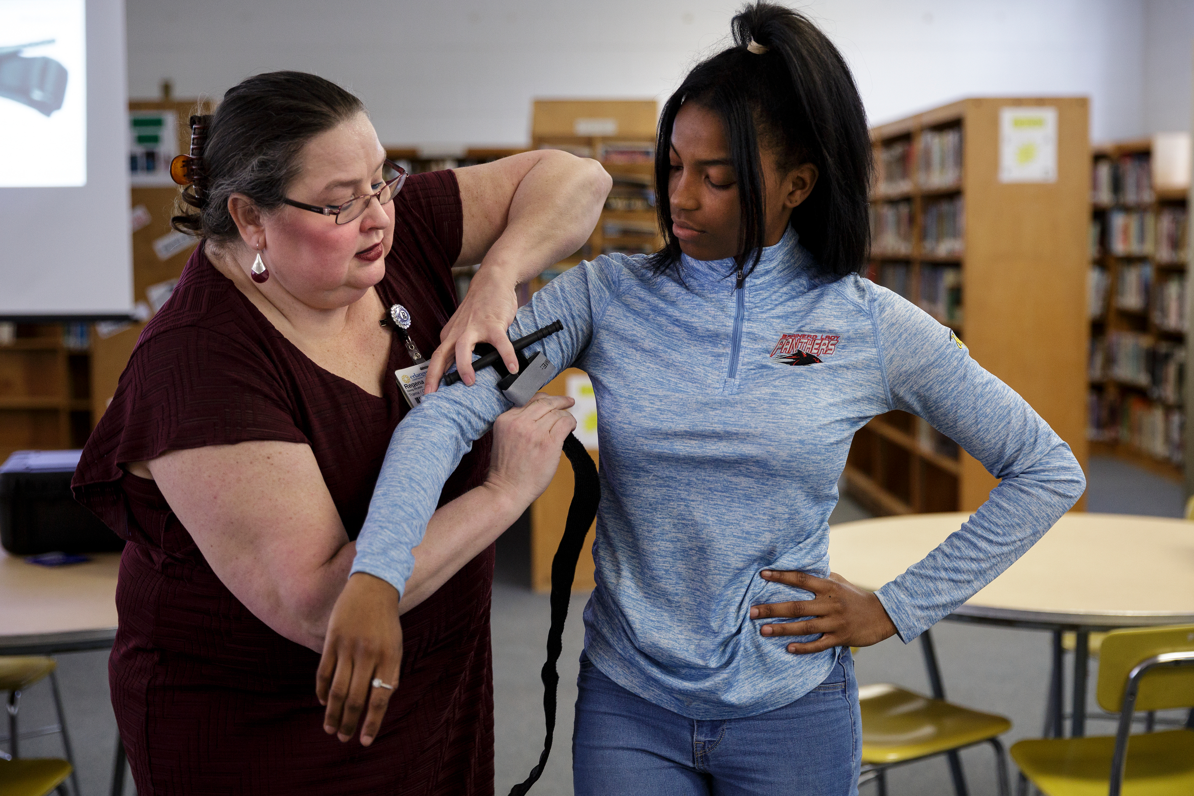 Nurse Regena Young, left, demonstrates tying a tourniquet with student Apre'l Ward during a