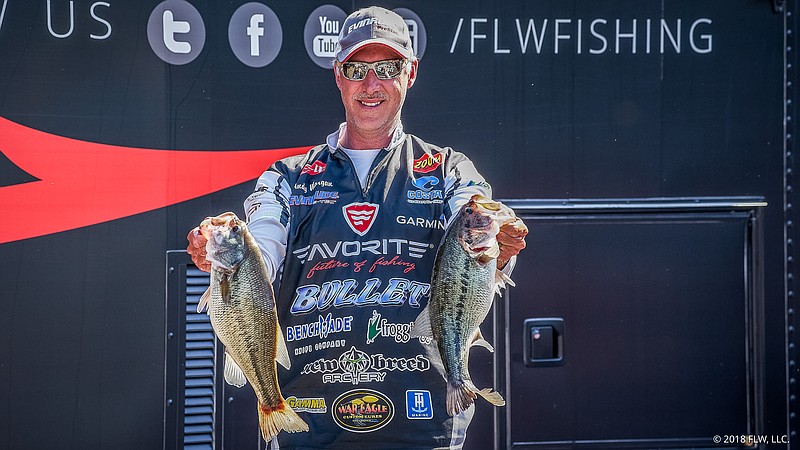 Andy Morgan of Dayton, Tenn., holds two of his five "gorgeous" keepers that gave him the first-day lead Thursday in the FLW Tour bass tournament on Lake Cumberland.