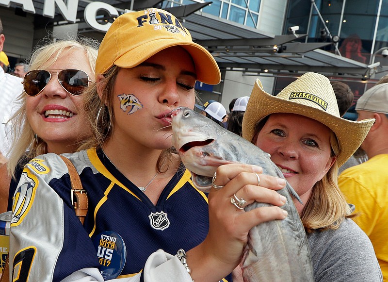 FILE - In this June 5, 2017, file photo, Nashville Predators fan Anna Claire Massey kisses a catfish as fans celebrate before Game 4 of the NHL hockey Stanley Cup Finals between the Nashville Predators and the Pittsburgh Penguins, in Nashville, Tenn. 