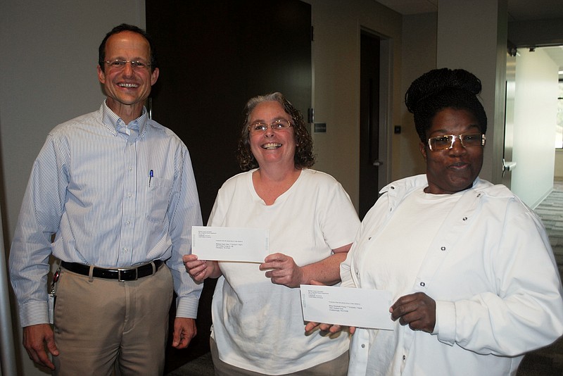 Rusty McKee, executive vice president of manufacturing, left, appears with packaging technicians Melissa Gwen Allen and Mary Peavy, from left, after McKee full-time workers received checks for $1,000 each