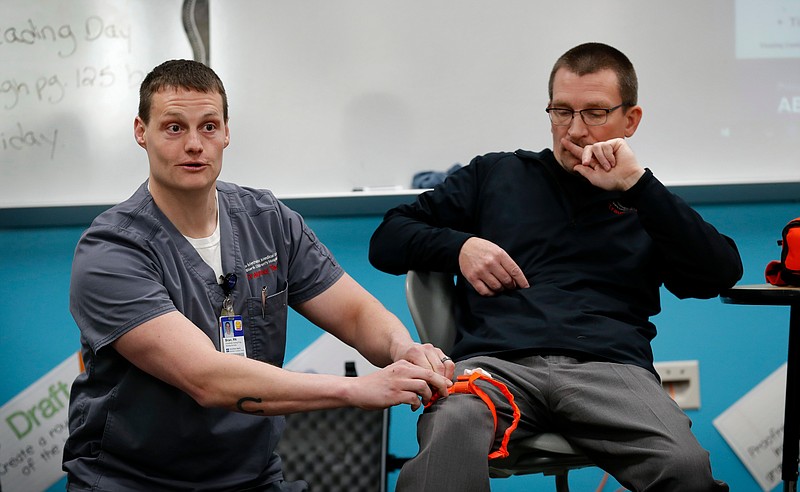 In this March 28, 2018, photo, trauma care specialist Brian Feist and Dr. Richard Sidwell lead a medical training session for teachers and staff at Southeast Polk High School in Pleasant Hill, Iowa. With school shootings a regular occurrence, educators across the country are learning techniques to help victims survive by stemming blood loss. Feist and Sidwell are among those helping educators learn skills in medical training through a nonprofit program, dubbed Stop the Bleed. (AP Photo/Charlie Neibergall)