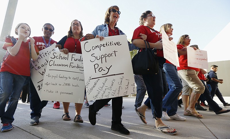 Teachers at Tuscano Elementary School stage a "walk-in" for higher pay and school funding Wednesday, April 11, 2018, in Phoenix. Teachers gathered outside Arizona schools to show solidarity in their demand for higher salaries staging "walk-ins" at approximately 1,000 schools that are part of a statewide campaign for a 20 percent raise and more than $1 billion in new education funding. (AP Photo/Ross D. Franklin)