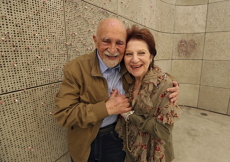 In this Wednesday, April 11, 2018, photo, childhood Holocaust survivors Simon Gronowski and Alice Gerstel Weit hug at the Los Angeles Holocaust Museum memorial. There was much hugging, kissing and crying Wednesday as the two old friends held hands tightly while sitting outside on a museum patio to share memories from a long-ago past. (AP Photo/Reed Saxon)