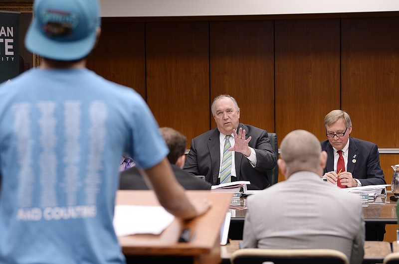 John Engler, center, interim President of Michigan State University, tells Dan Martel, 21, President of MSU college democrats, that his allotted speaking time of five minutes is up during a university board meeting, Friday, April 13, 2018, Lansing, Mich. Engler said Friday that he regrets the school's response to a woman filing a federal rape lawsuit against the university. (Clarence Tabb Jr./Detroit News via AP)

