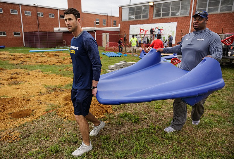 UTC head football coach Tom Arth, left, and defensive line coach Davern Williams carry a piece of equipment during a volunteer day to construct a playground at the Chattanooga Charter School of Excellence lower school on East 23rd Street on Saturday, April 14, 2018, in Chattanooga, Tenn. Volunteers, including University of Tennessee at Chattanooga football players and coaches, helped assemble the new playground equipment over the course of the day.