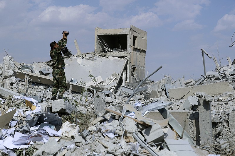 A Syrian soldier films the damage of the Syrian Scientific Research Center which was attacked by U.S., British and French military strikes to punish President Bashar Assad for suspected chemical attack against civilians, in Barzeh, near Damascus, Syria, Saturday, April 14, 2018.