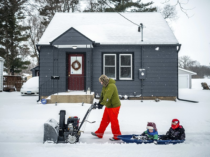 Paul Tuchtenhagen uses a snow blower to pull Leland, 2, and Ephram, 5, in a sled during a storm, Sunday, April 15, 2018, in Rochester, Minn. A deadly storm system moving through the central and southern U.S. has dumped a thick blanket of snow on parts of Minnesota, Wisconsin and South Dakota and left parts of Michigan an icy mess. (Joe Ahlquist/The Rochester Post-Bulletin via AP)