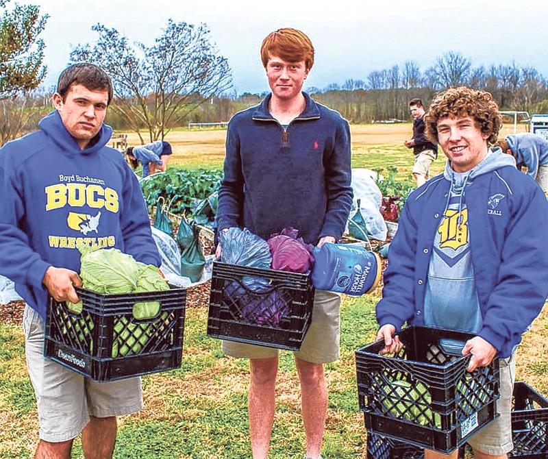 Will Watkins, Gage Baker and Jax Price, from left, showcase some of the produce students grow on campus, which is used in the food they eat at school.