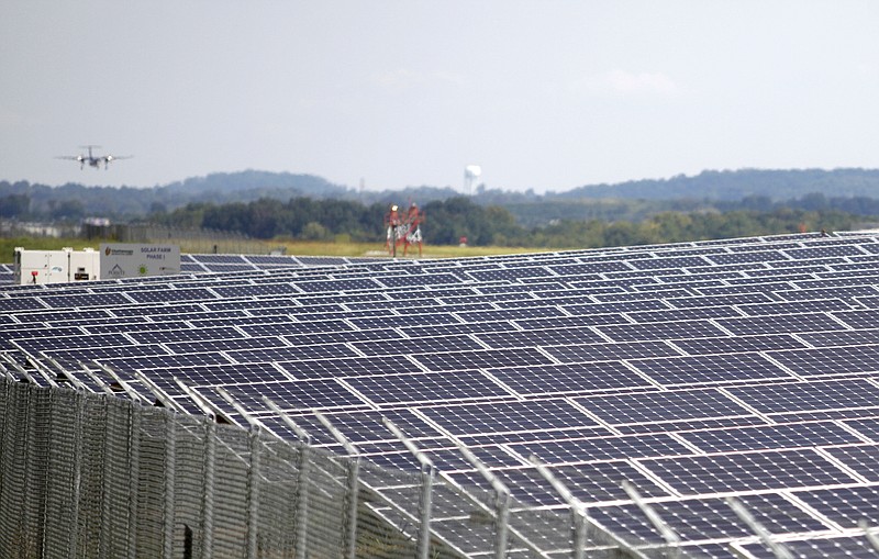 An airplane flies into Chattanooga Metropolitan Airport in the background as part of Lovell Field's solar farm is seen near the runway.